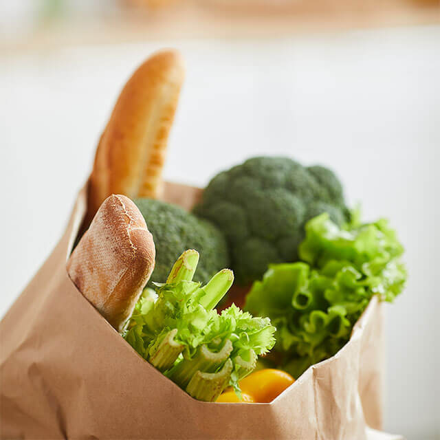 fresh vegetables and groceries in a brown bag